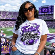 Load image into Gallery viewer, Woman wearing a custom purple, black, and white Football Mom shirt with retro lettering and a football graphic at a stadium